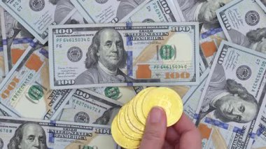 Yüzlerce dolarlık banknotların yakın plan görüntüsü, bitcoinler bir yüzeye saçılmış. Faturalar, değerlerini ve para birimlerini vurgulayarak karmaşık tasarımlar ve canlı renkler sergiliyor..