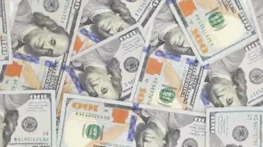 Birden fazla yüz dolarlık banknotların yakın plan görüntüsü bir araya toplanmış ve daire şeklinde hareket ediyor. Yasa tasarıları karmaşık tasarımlar ve canlı renkler sergiliyor, para ve finansmanı vurguluyor.