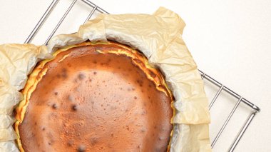 Beyaz arka planda çatlakları olan ev yapımı lezzetli fırınlanmış cheesecake 'in göz kamaştırıcı üst görüntüsü.