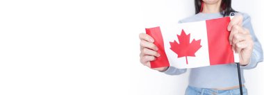 Gri arka planda küçük Kanada bayrağı taşıyan beyaz tişörtlü tanınmamış kız çocuğu, Kanada günü, tatil, oy, göç, vergi, kopya alanı.