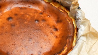 Beyaz arka planda çatlakları olan ev yapımı lezzetli fırınlanmış cheesecake 'in göz kamaştırıcı üst görüntüsü.