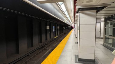 Toronto, Kanada - 29 Haziran 2025: Metro istasyonu platformu, modern bir kentsel ulaşım sahnesi yaratan sarı bir güvenlik hattı, boş raylar ve parlak mimari unsurlara sahiptir.