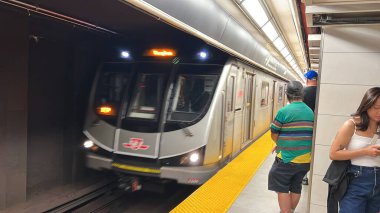 Toronto, Kanada - 29 Haziran 2025: Metro TTC treni metro istasyonuna yaklaşırken, yolcular platformda bekliyor, kentsel ulaşım sistemi ve günlük trafiğin yoğunluğu vurgulanıyor