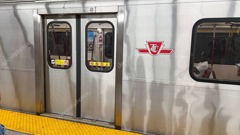 Toronto, Canada - June 29, 2025: Subway train doors in Toronto feature TTC logo, vibrant yellow platform enhances urban transit atmosphere