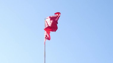 Kırgızistan 'ın açık mavi gökyüzünde dalgalanan kırmızı bayrağı. Bayrak, Kırgız halkının 40 kabilesini sembolize eden merkezde 40 vatozlu sarı bir güneşe sahip..