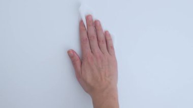 Bir el, el bezi ile el değmemiş beyaz bir yüzeyi nazikçe siliyor, günlük hayatta temizlik ve hijyenin önemini vurguluyor.