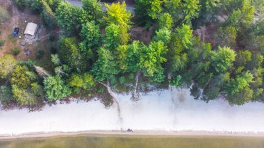 Görüntü, sabahları çok güzel bir göl kenarı kamp alanını gösteriyor. Kamp alanı yemyeşil ağaçlarla çevrili ve göl ince bir sis tabakasıyla örtülmüş. Huzurlu ve sakin bir atmosfer yaratıyor..