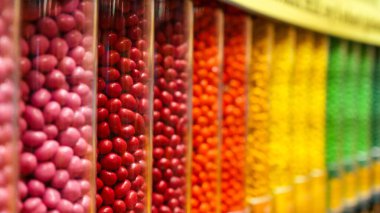 Temiz plastik kaplarda sergilenen renkli yuvarlak şekerler, düzenli bir sırada dizilmiş. Şekerleme endüstrisiyle ilgili geçmiş ve çizimler için mükemmel..