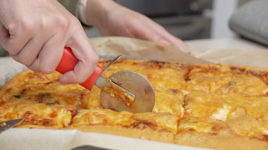 Yuvarlak bir bıçakla pizza kesmek. Lezzetli pizzanın parçalara ayrıldığı yakın plan çekimler. Yavaş çekimde bir pizzayı kesiciyle birden fazla dilime ayırmak.