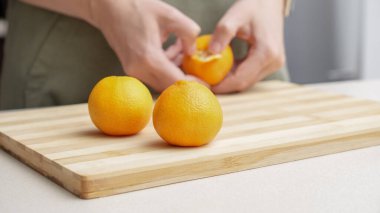 Masadaki kesme tahtasının üzerinde portakal kabuğu soyulmuş eller, Noel 'de yemek yapmak için bir sürü sulu taze meyve..