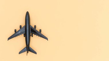 Şeftali arkaplanındaki siyah oyuncak bir uçağın yukarıdan çekimi. Bu izole görüntü seyahat, havacılık ve ulaşım temaları, uçuş ve keşif kavramları için uygundur..