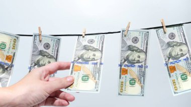 Para aklama kavramı. Yüz dolarlık banknotlar çamaşır ipinde asılı ve kuruyor. Mali suç, yasadışı faaliyet, gölge ekonomi. İş, finans ve suçla ilgili konular için kavram.
