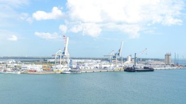 Fort Lauderdale FL, Amerika Birleşik Devletleri - 12 Şubat 2025: Açık mavi gökyüzü ve durgun suya karşı vinç ve kargo gemilerinin yer aldığı canlı bir sanayi limanı