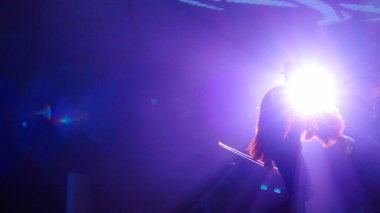 Dramatik ışıklandırma, güçlü bir varlıkla seyirciyi büyüleyen, sanatsal ve tutkulu bir performans sergileyen bir sanatçıyı vurguluyor.