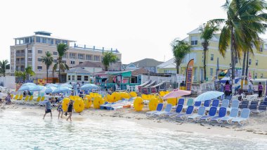 Nassau, Bahamalar - 14 Şubat 2025: Güneş pansiyonları, şemsiyeler ve sıcak tropikal atmosferin tadını çıkaran insanların yer aldığı canlı plaj sahnesi