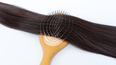 Saç uzantıları ahşap bir fırçada zarif bir şekilde düzenlenmiştir. Parlak dokularını ve uzunluklarını, güzellik ve saç şekillendirme temaları için birebirdir.