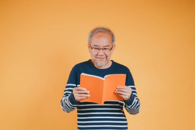 Mutlu son sınıf öğrencisi gülümseyen ve kitap eğitimi bilgisi okuyan mutlu bir erkek. Renkli arka plan öğreniyor..