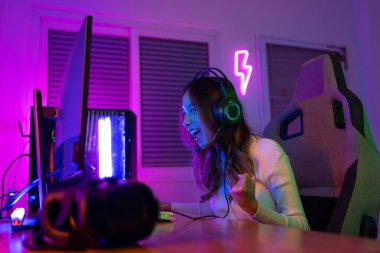 Online video oyunu oynayan Asyalı oyuncu PC 'de ışıklandırma efektiyle heyecanlanıyor, evde canlı yayın yapıyor. Oyuncu ve E-Sport çevrimiçi oyun teknolojisi şampiyonluk turnuvası oyuncu konsepti.