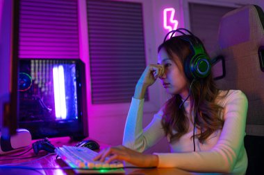 Gözler yorgun. Asyalı bir kadının çevrimiçi video oyunu oynadığı oyuncu ve E-Sport çevrimiçi ışıklandırma efektiyle, evinde canlı yayın yapıyor. Uzun süre ekrana bakmaktan gözleri yoruldu..