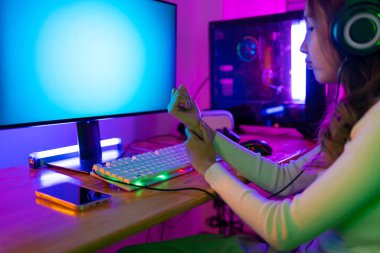 Bilek ağrısı konsepti. Asyalı bir kadının çevrimiçi video oyunu oynadığı oyuncu ve E-Sport çevrimiçi ışıklandırma efektiyle, evinde canlı yayın yapıyor. Uzun zamandır bileğini kullanıyor..