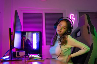 Gençler Sırt Ağrısı. Asyalı bir kadının çevrimiçi video oyunu oynadığı oyuncu ve E-Sport çevrimiçi ışıklandırma efektiyle, evinde canlı yayın yapıyor. Uzun süre oturduğu için sırt ağrısı çekiyor.