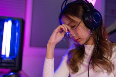 Gözler yorgun. Asyalı bir kadının çevrimiçi video oyunu oynadığı oyuncu ve E-Sport çevrimiçi ışıklandırma efektiyle, evinde canlı yayın yapıyor. Uzun süre ekrana bakmaktan gözleri yoruldu..