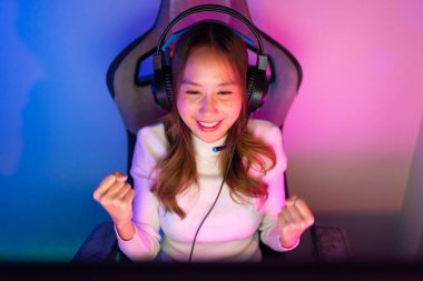 Online video oyunu oynayan Asyalı oyuncu PC 'de ışıklandırma efektiyle heyecanlanıyor, evde canlı yayın yapıyor. Oyuncu ve E-Sport çevrimiçi oyun teknolojisi şampiyonluk turnuvası oyuncu konsepti.