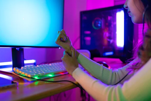 stock image Wrist pain concept. Gamer and E-Sport online of Asian woman playing online computer video game with lighting effect, broadcast streaming live at home. her use her wrist for a long time.