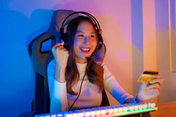stock image Top up online game with credit card concept. Gamer and E-Sport online of Asian woman playing online computer video game with lighting effect, broadcast streaming live at home. Gamer and E-Sport gaming