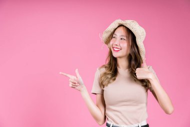 Heyecanlı başarı başarısı ve mutlu Asyalı genç bir kadının pembe arka planda gülümseyişi.