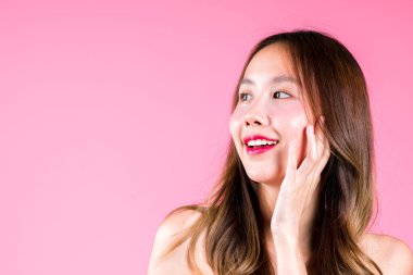 Göz altı gençleştirme, yüz bakımı, güzel Asyalı bir kadının pembe arka plana konsept sürmesi.