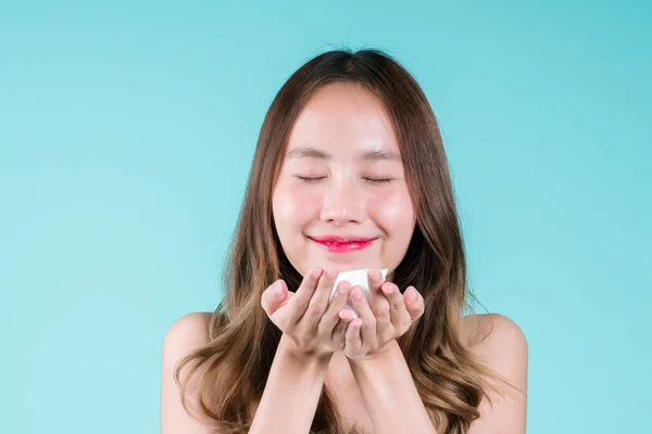 快乐迷人的年轻亚洲女人在蓝色背景的脸上用泡沫清洁剂洗净和擦拭 — 图库照片