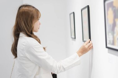 Sanat galerisini ziyaret eden bir kadın duvardaki resimleri sanat müzesindeki resim çerçevesi insan yaşam tarzı kavramını izliyor..