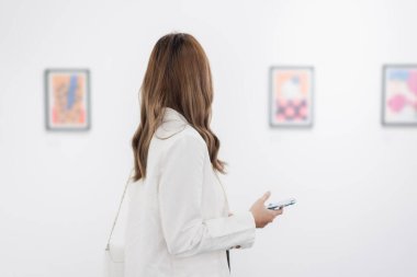 Sanat galerisini ziyaret eden bir kadın duvardaki resimleri sanat müzesindeki resim çerçevesi insan yaşam tarzı kavramını izliyor..