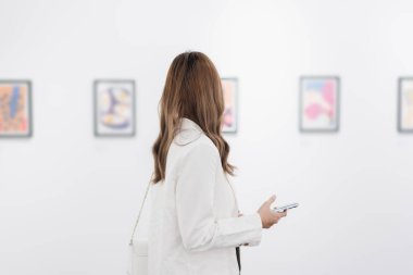 Sanat galerisini ziyaret eden bir kadın duvardaki resimleri sanat müzesindeki resim çerçevesi insan yaşam tarzı kavramını izliyor..