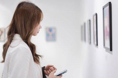 Sanat galerisini ziyaret eden bir kadın duvardaki resimleri sanat müzesindeki resim çerçevesi insan yaşam tarzı kavramını izliyor..