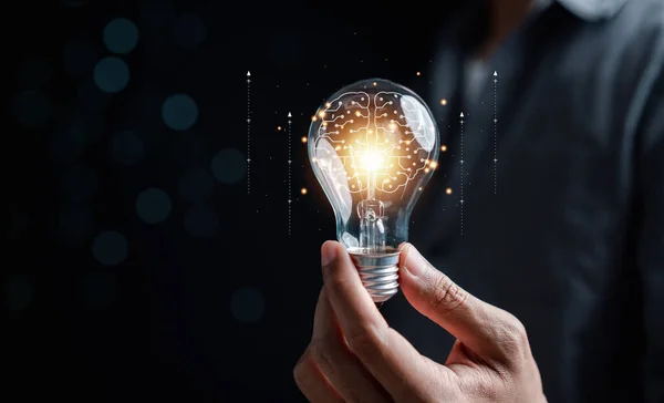 stock image Hand man holding illuminated lightbulb, idea, innovation and inspiration with glowing virtual brain, smart intelligent creativity with bulbs, Motivation and innovation concept.