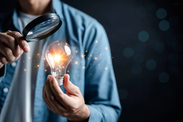 Businessman focus with magnifying to light bulb with business target planning idea and creativity innovation development leadership investment growth and success development, goal, strategy
