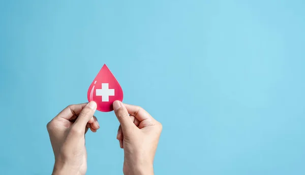 stock image hands holding blood drop paper cut, blood transfusion, world blood donor day, red cross to give blood.world hemophilia day concept