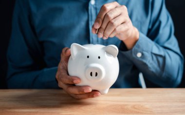 Yatırım bankacılığı, emeklilik planlama gelecek tasarrufu, kâr ve faiz konsepti için yatırım yapmak için beyaz kumbaraya para koyan adam..