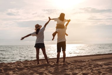 Mutlu Asyalı aile, baba, anne ve kızının yaz tatilinde okyanus plajında plaj oynarken deniz sahilinin tadını çıkarıyor. Tatillerde mutlu aile yaşam tarzı konsepti.