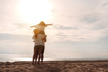 Mutlu Asyalı aile, baba, anne ve kızının yaz tatilinde okyanus plajında plaj oynarken deniz sahilinin tadını çıkarıyor. Tatillerde mutlu aile yaşam tarzı konsepti.