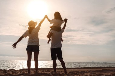 Mutlu Asyalı aile, baba, anne ve kızının yaz tatilinde okyanus plajında plaj oynarken deniz sahilinin tadını çıkarıyor. Tatillerde mutlu aile yaşam tarzı konsepti.