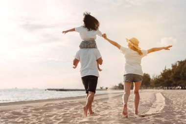 Mutlu Asyalı aile, baba, anne ve kızının yaz tatilinde okyanus plajında plaj oynarken deniz sahilinin tadını çıkarıyor. Tatillerde mutlu aile yaşam tarzı konsepti.