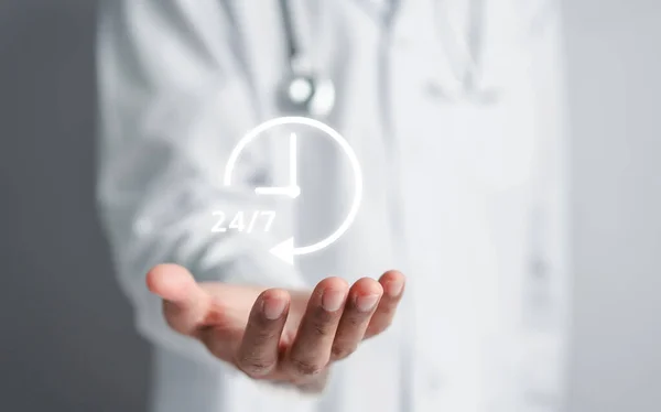 Doctor in a white coat uniform holding 24/7 service icon for assistance patient when accident or emergency, Medical call center service without interruption day and night.