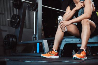 Spor salonunda egzersiz yapmak, spor yaptıktan sonra dambıl ve su şişesiyle dinlenmek sağlıklı bir vücut geliştirme..