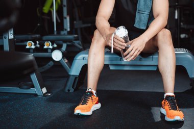 Spor salonunda egzersiz yapmak, spor yaptıktan sonra dambıl ve su şişesiyle dinlenmek sağlıklı bir vücut geliştirme..