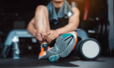 Spor salonunda egzersiz yapmak, spor yaptıktan sonra dambıl ve su şişesiyle dinlenmek sağlıklı bir vücut geliştirme..