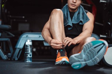 Spor salonunda egzersiz yapmak, spor yaptıktan sonra dambıl ve su şişesiyle dinlenmek sağlıklı bir vücut geliştirme..