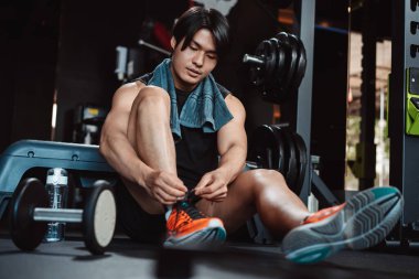 Spor salonunda egzersiz yapmak, spor yaptıktan sonra dambıl ve su şişesiyle dinlenmek sağlıklı bir vücut geliştirme..